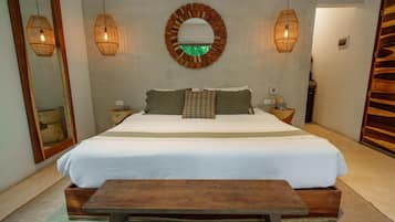 A bedroom with a large bed, two bedside tables, a wooden bench, a round mirror, and two wall-mounted lamps.