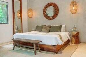 Une chambre à coucher comprenant un lit, des tables de chevet, un banc, un miroir et des lampes fixées au mur.
