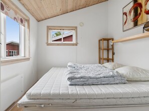 Une chambre à coucher avec un lit, une fenêtre, un cadre photo et une étagère.