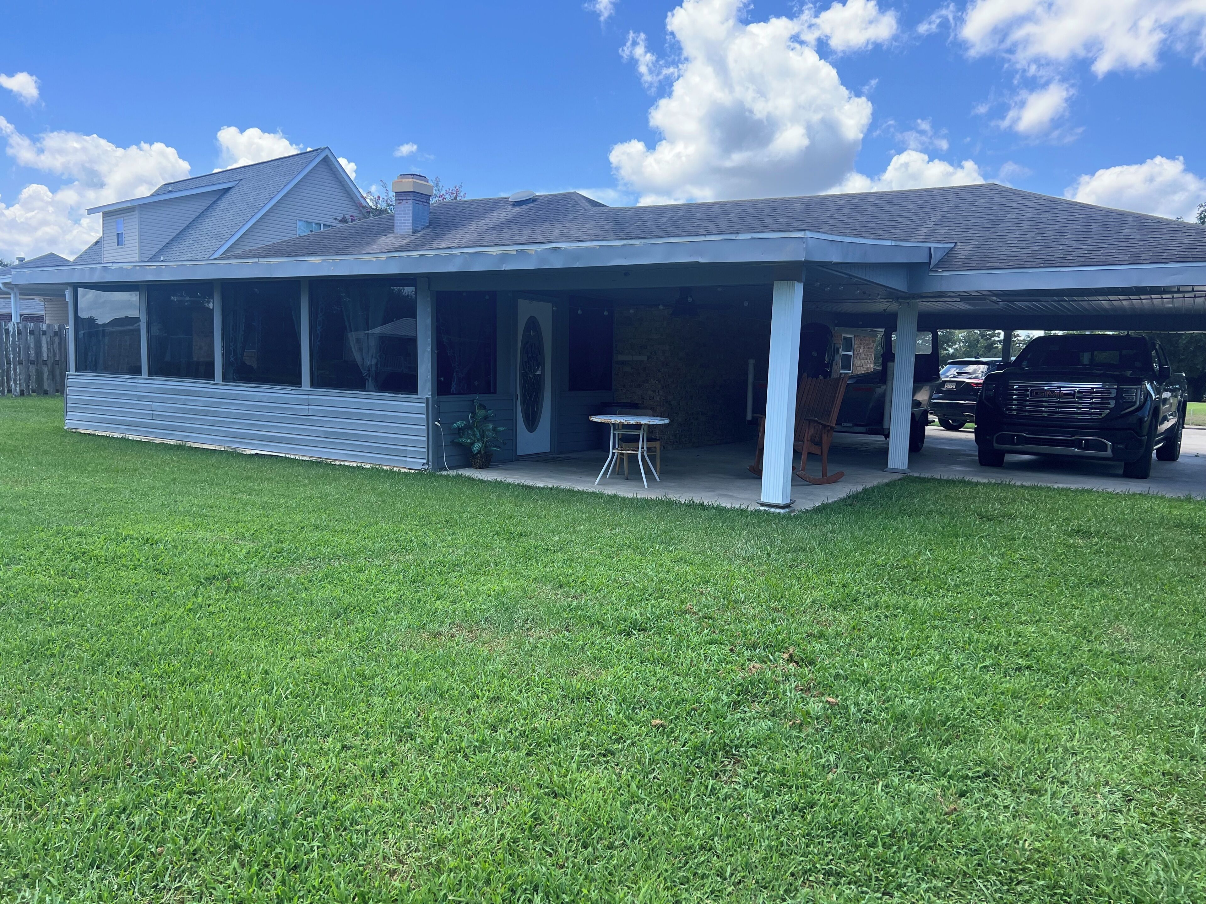 Une maison moderne dotée d’un patio couvert, d’un garage et d’une pelouse.