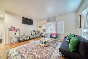 A living room with a sofa, a coffee table, and a TV mounted on the wall. - Cozy 2BR Long Beach Retreat (Long Beach)