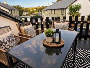 Een terras met rieten meubels, een tafel met kaars en lantaarn, en lichtjes.
