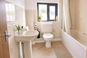 Een badkamer met een wastafel, toilet, raam en douche.