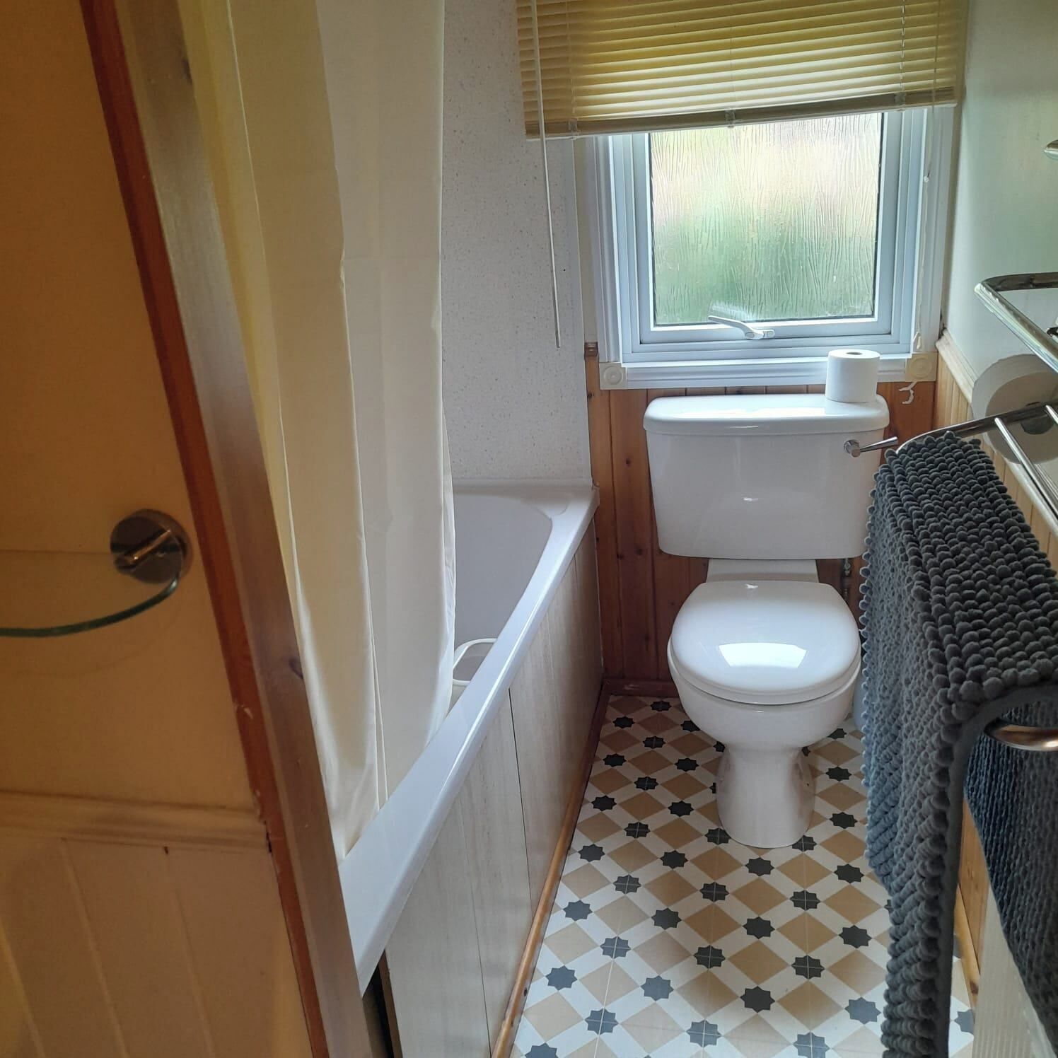 Ein kleines Badezimmer mit Toilette, einer Badewanne und einem Fenster mit Jalousien.