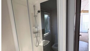 A glass-enclosed shower area with a handheld showerhead and a wall-mounted faucet. - Cabin - Sleeps 8 - Garden and Parking (St. Leonards-on-Sea)