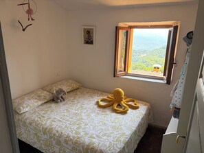 Ein Schlafzimmer mit einem Bett, einem Fenster mit Blick, einer Tür und einer Wand mit einem Bild.