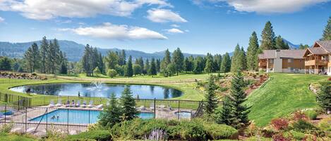 A resort with a swimming pool, a golf course, and a mountain backdrop.