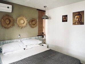 A bedroom with a bed, pillows, a wall-mounted air conditioner, a hanging lamp, and two wall-mounted pictures. - Stylish couples Beach Escape in Pointe aux Canonniers (Pointe aux Canonniers)