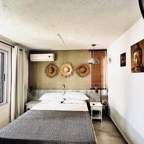 Ein Schlafzimmer mit einem Bett, einem Nachttisch, einer Wandlampe und einer Buddha-Statue.