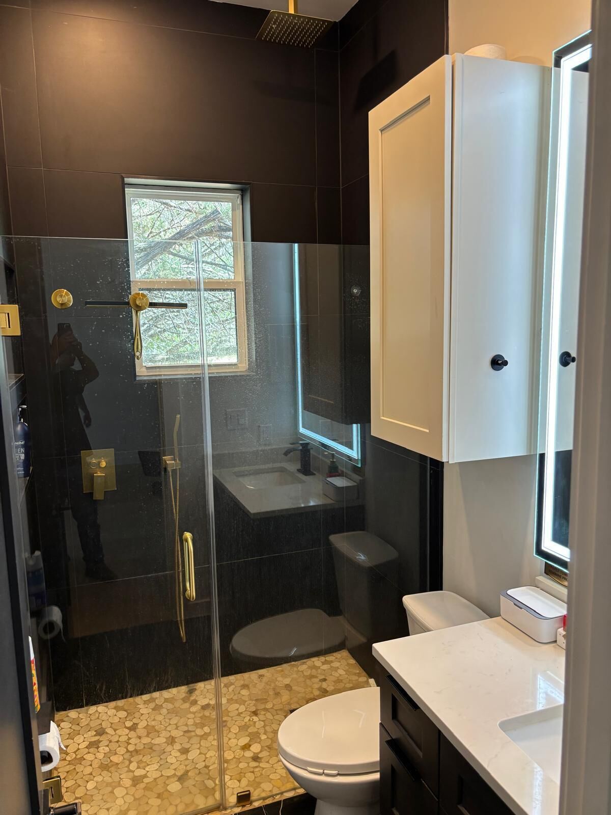 Un baño moderno con ducha envuelta en vidrio, inodoro y lavamanos.