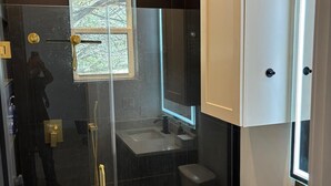 Un baño moderno con ducha envuelta en vidrio, inodoro y lavamanos.