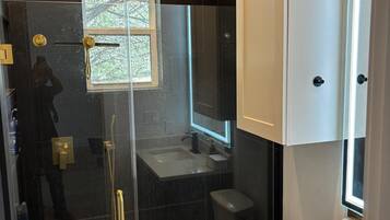 Un baño moderno con ducha envuelta en vidrio, inodoro y lavamanos.