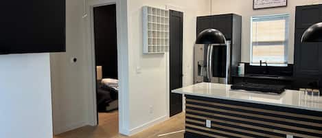 Cocina moderna con una isla central, refrigerador empotrado y un comedor con una silla negra.