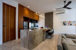 A modern kitchen with a central island, wooden cabinets, and a built-in refrigerator. - Pantai Lima 2BR Villa - Rooftop - 500m to Beach (Badung)
