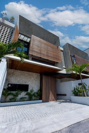 A modern multi-story building with a flat roof, large windows, and a stone facade. - Pantai Lima 2BR Villa - Rooftop - 500m to Beach (Badung)