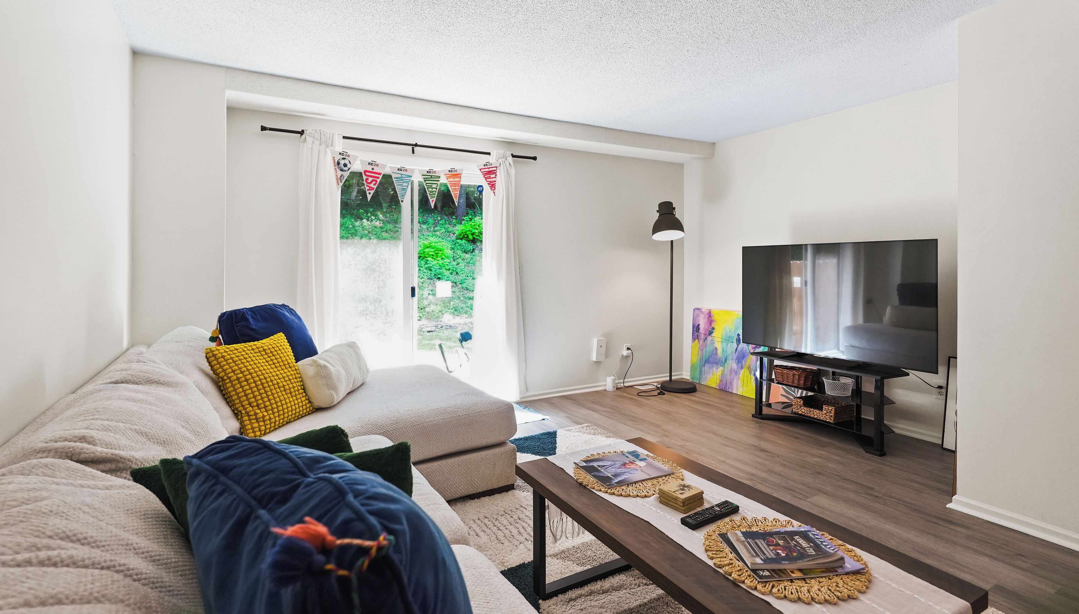 A living room with a sofa, coffee table, TV, and artwork on the wall.
