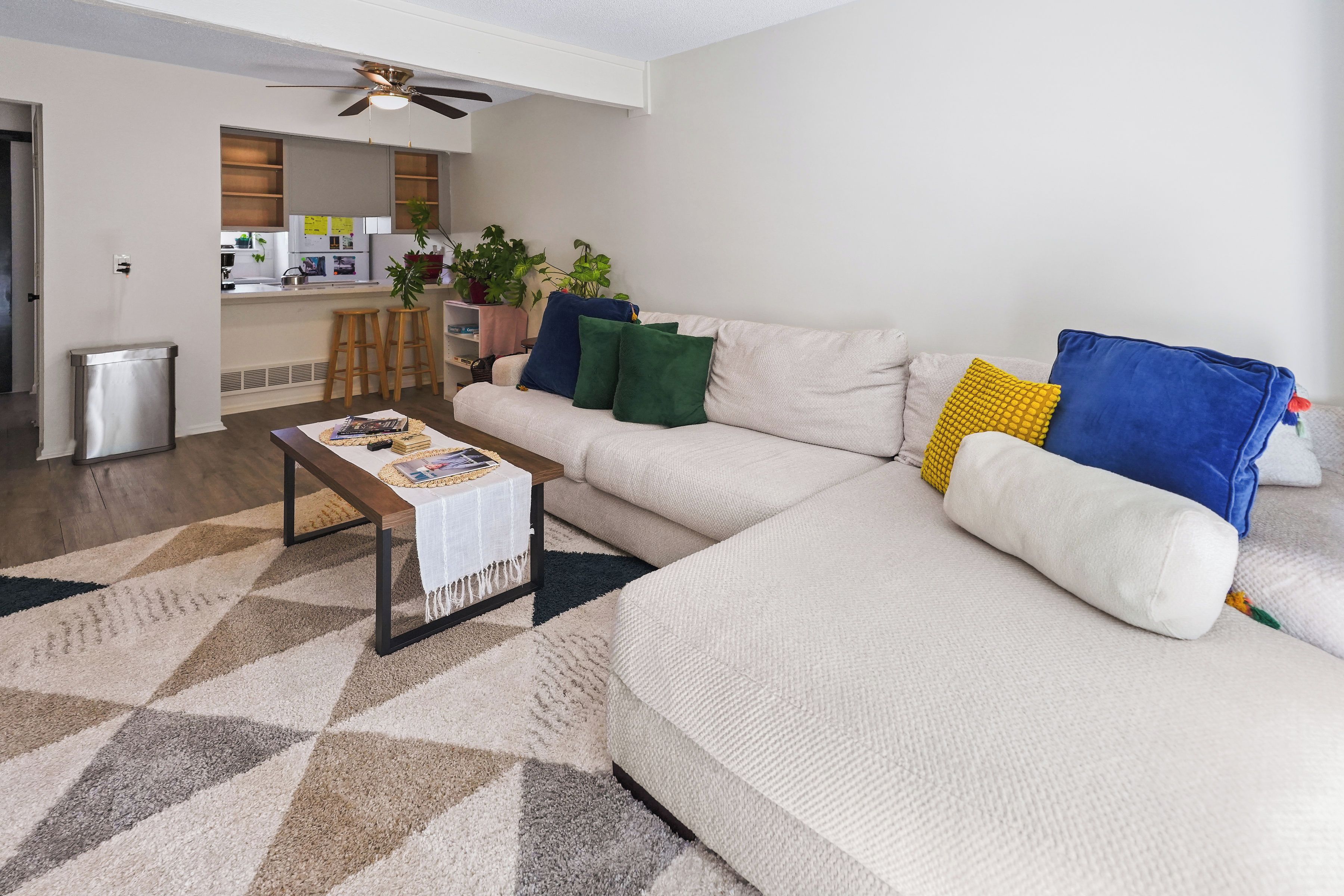 A modern living room with a sectional sofa, a coffee table, and a kitchen in the background.