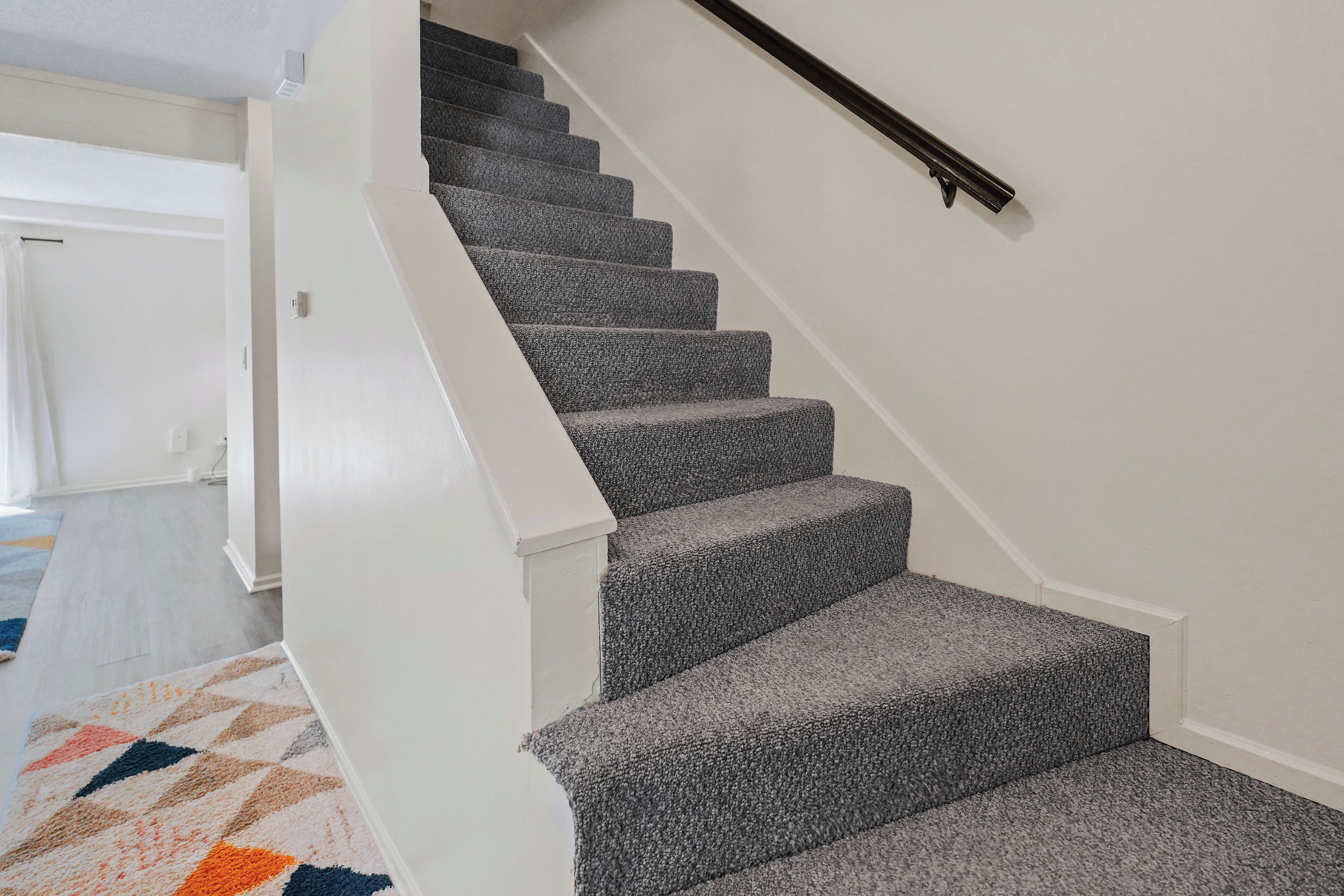 A staircase with carpeted steps and a handrail, leading to a landing.