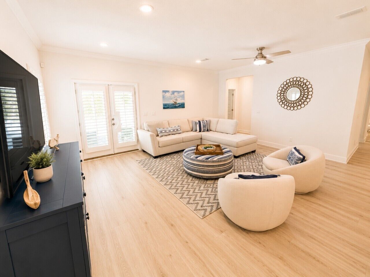 A spacious living room with a sofa, two armchairs, a coffee table, and a television.