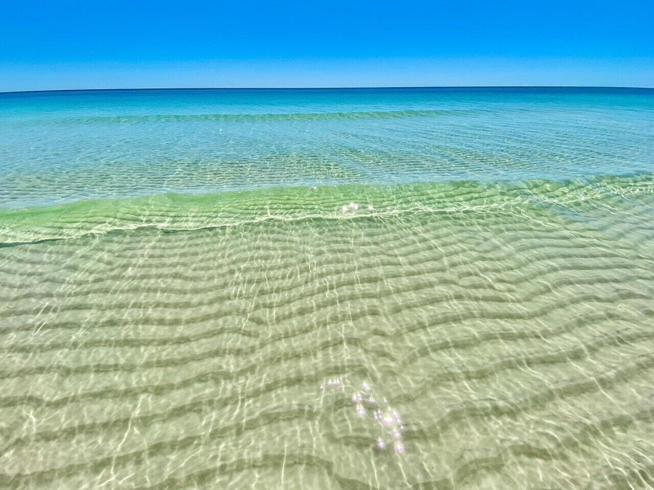 Une vue dégagée sur une plage, avec une eau peu profonde et un horizon lointain.