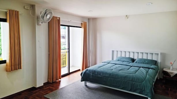 Un dormitorio con cama, ventilador, puerta corredera de vidrio y radiador blanco.