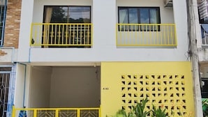 Un edificio de dos plantas con balcones y un portón amarillo.