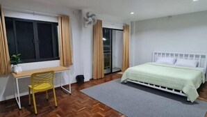 Un dormitorio con una cama, un escritorio, una silla y una ventana.