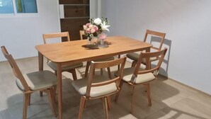 Una mesa de comedor de madera con seis sillas, un jarrón con flores y una lámpara de mesa pequeña.