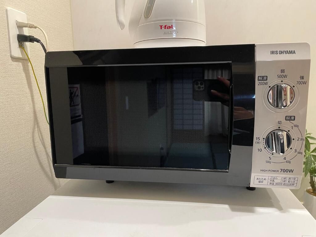A black microwave oven with a digital display and control panel, placed on a white countertop.