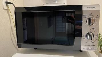 A black microwave oven with a digital display and control panel, placed on a white countertop.