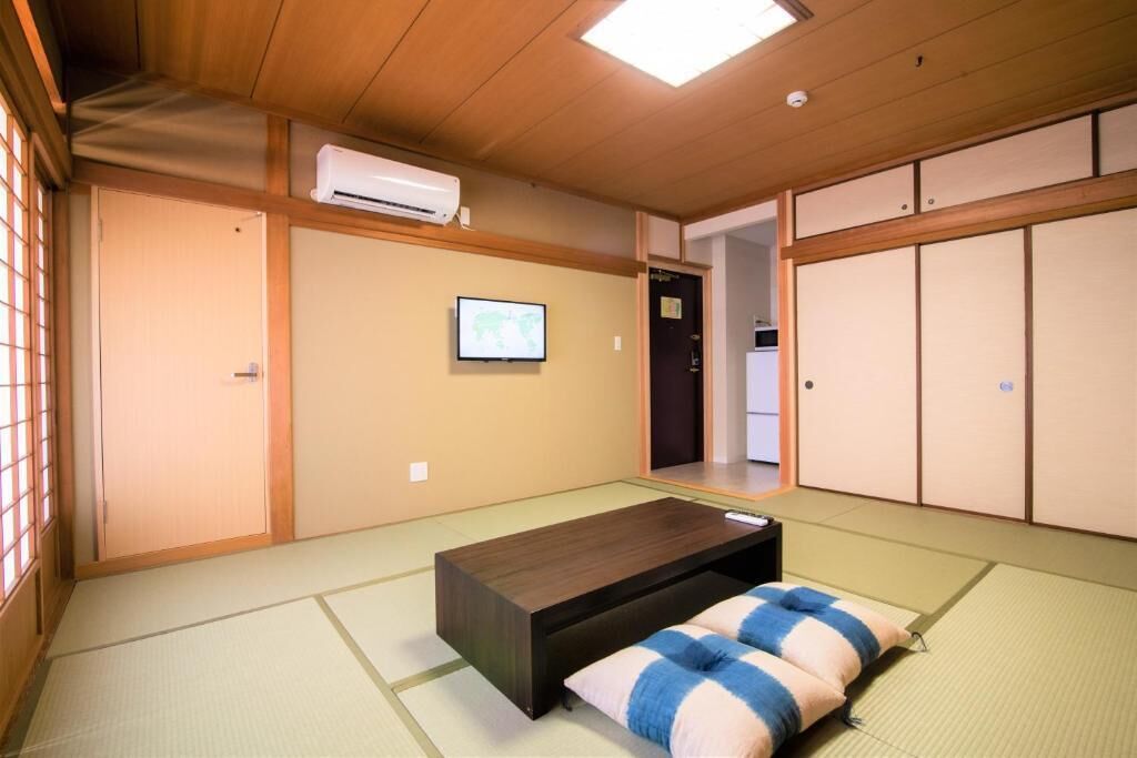 A traditional Japanese room with tatami flooring, a low wooden bed, a television, and sliding doors.