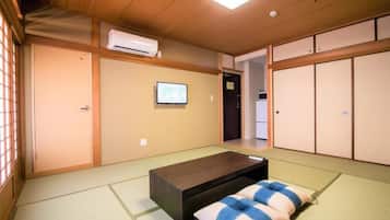 A traditional Japanese room with tatami flooring, a low wooden bed, a television, and sliding doors.