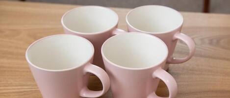 Quatre tasses en céramique rose sur une table en bois.