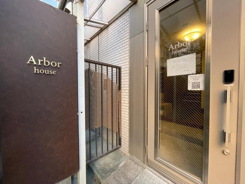 Une entrée d’immeuble avec une enseigne indiquant « Arbor House » et un code QR sur la porte vitrée.