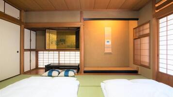 Una tipica stanza giapponese con pavimenti in tatami, un letto a piattaforma basso, porte scorrevoli e un paravento shoji.