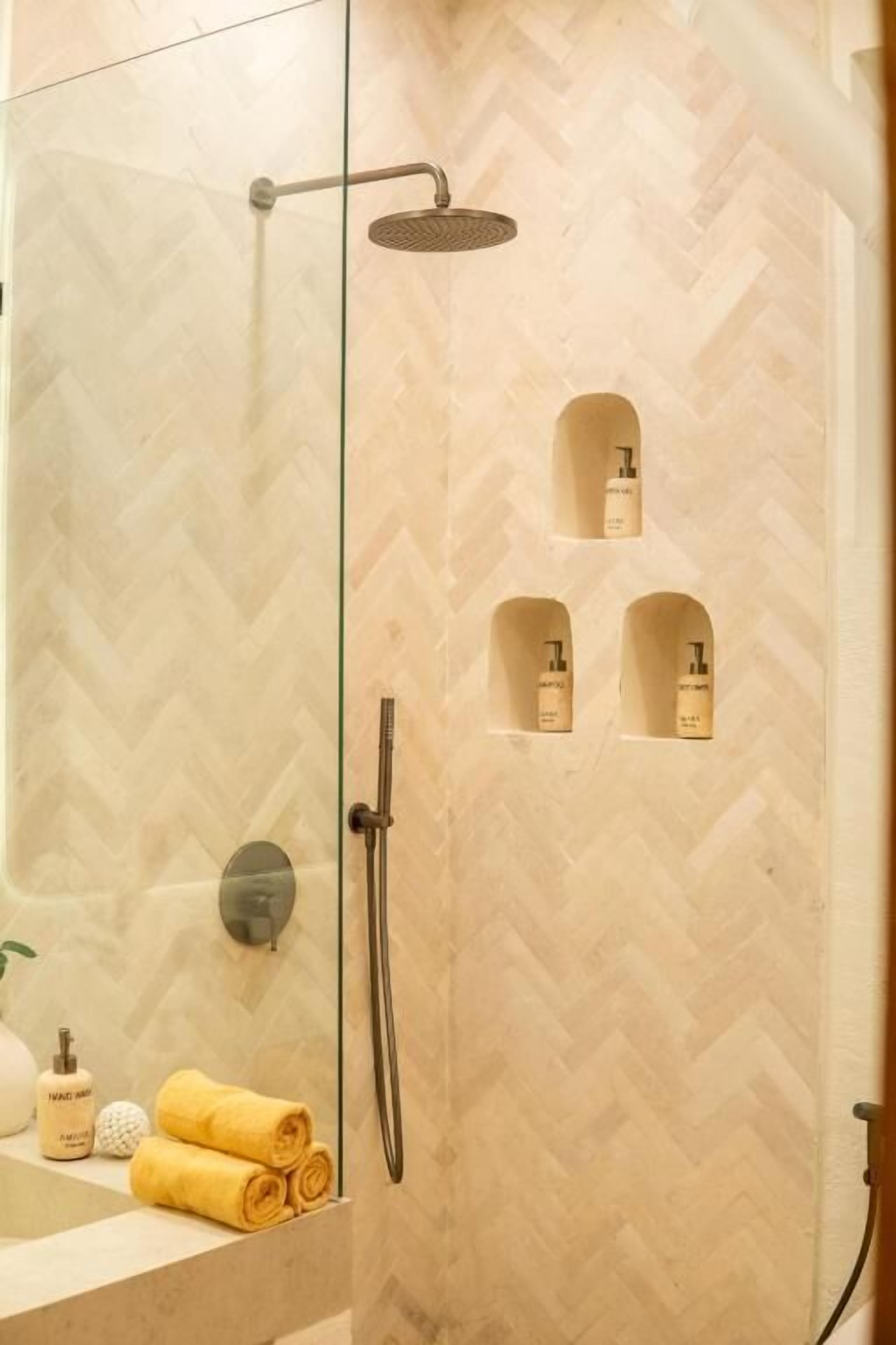A shower with a handheld showerhead and a wall-mounted faucet.