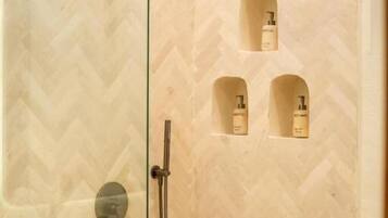 A shower with a handheld showerhead and a wall-mounted faucet.