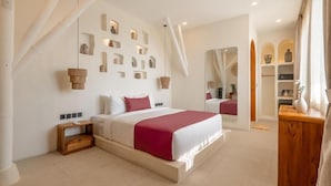 Ein modernes Schlafzimmer mit einem großen Bett, einem Holznachttisch, einem Spiegel und einer Wand mit Regalen.