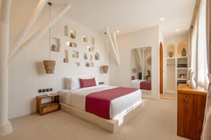 A modern bedroom with a large bed, a wooden nightstand, a mirror, and a wall with shelves. - Amara Ocean Living Uluwatu Padang Padang (Badung)