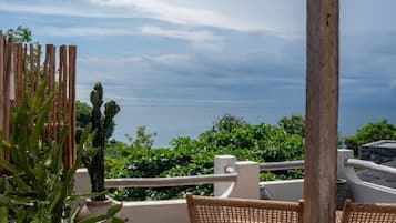 A balcony with wicker furniture, a wooden fence, and a view of the sea.