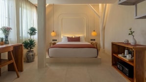 Ein modernes Hotelzimmer mit einem zentrierten Bett, begleitet von einem Holztisch und einer eingebauten Ablage mit einer Kaffeemaschine.