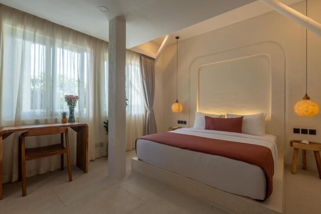 A modern bedroom with a large bed, bedside tables, a desk, and a window with curtains.