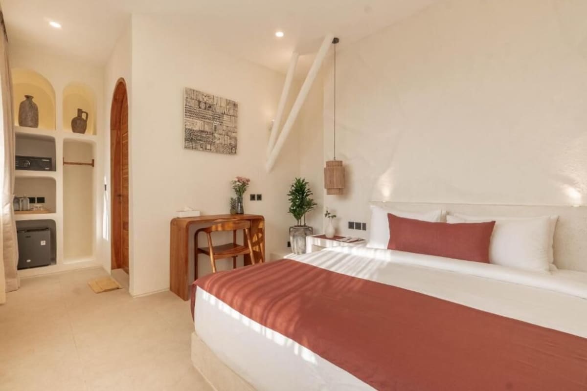 A bedroom with a large bed, a desk, and a chair.