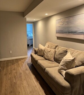 A living room with a beige sofa, wooden flooring, and a painting on the wall. - Beach Blessing - Short Walk to Beach and Coligny
2 bedroom, 2 bath condo (Hilton Head Island)