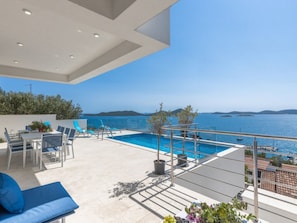 A rooftop pool area with a clear view of the sea, a dining setup, and a lounge chair. - Luxury villa Fleur with pool by Interhome (Drage)