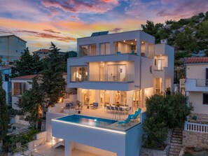 A modern multi-story residential building with a rooftop pool and outdoor seating area. - Luxury villa Fleur with pool by Interhome (Drage)