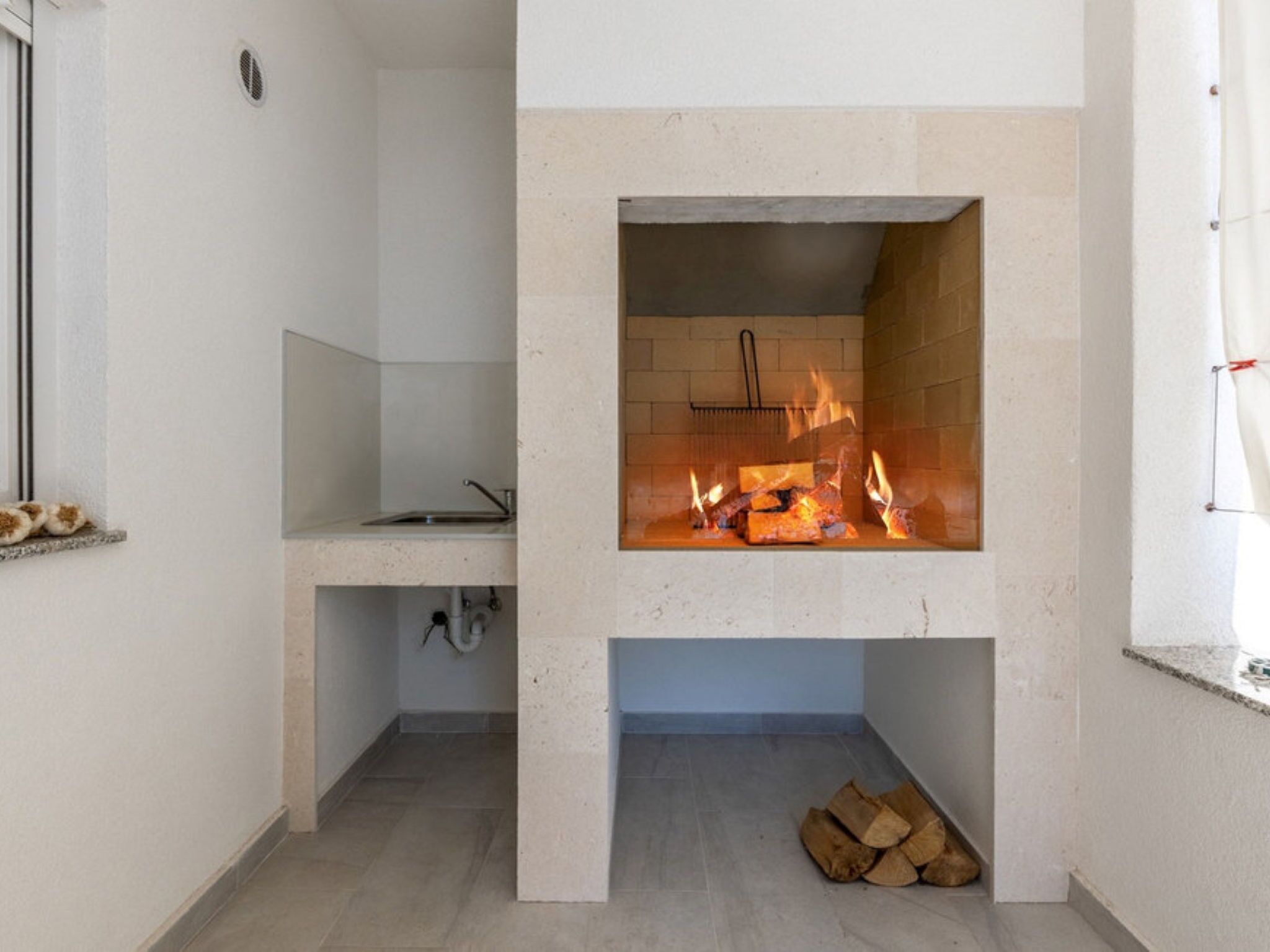Een moderne keuken met een inbouwvuurplaats, een raam en een spoelbak.
