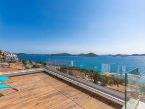 A balcony with a wooden floor, overlooking a body of water and distant land. - Luxury villa Fleur with pool by Interhome (Drage)