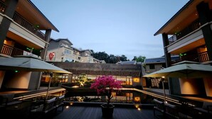 Un patio con mesas al aire libre, una fuente decorativa y un edificio con fachada tradicional al fondo.