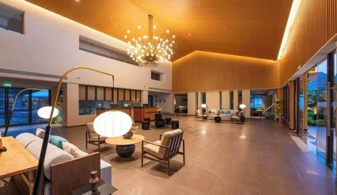 A spacious lobby with a modern chandelier, seating areas, and large windows.